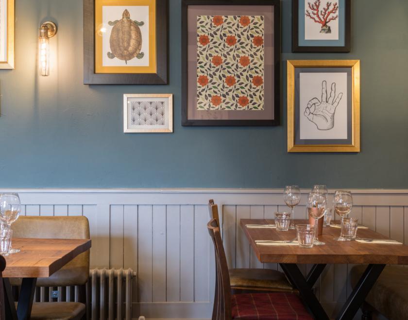 Picture of resturant, tables chairs and pictures on wall.