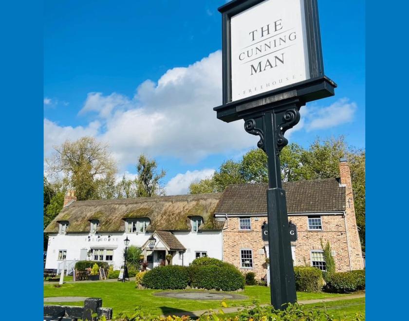 Exterior shot of the Cunning Man pub with a sign in the foreground