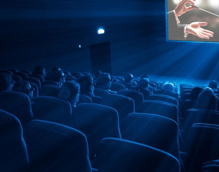 people in a cinema looking at the screen, featuring a conductor's baton
