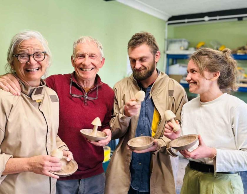 A smiling family of a mum, dad and 2 grown up children enjoying their woodturning day.