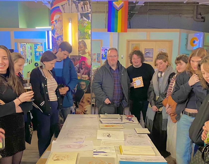 A group of people standing round a table covered in drawings