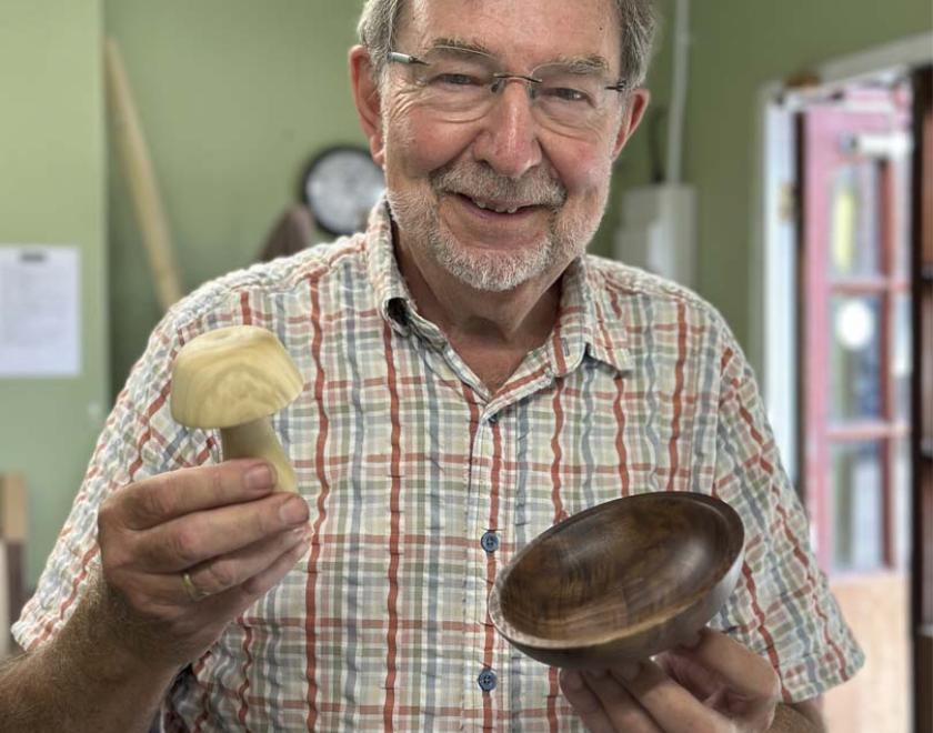 A man holding his turned wooden mushroom and bowl.