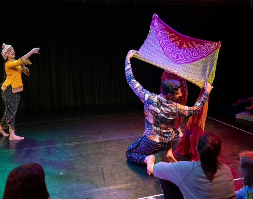 Photo of the same performers holding up colourful scarves and dancing