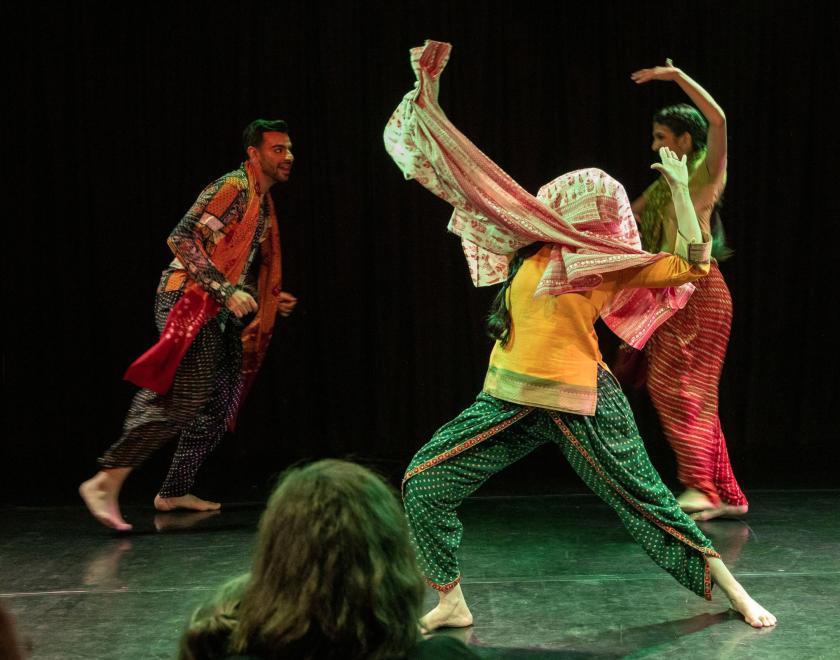 Photo of one of the performers holding a dramatic pose with a scarf around their head. 