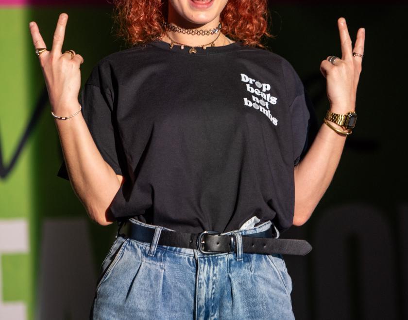 Photo of an actor on stage, standing with both hands up making the two-fingered 'up yours' sign.