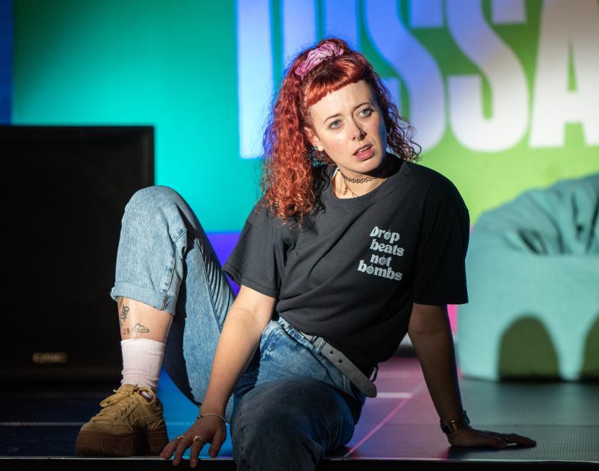 Photo of an actor sitting on stage in a slouched position.