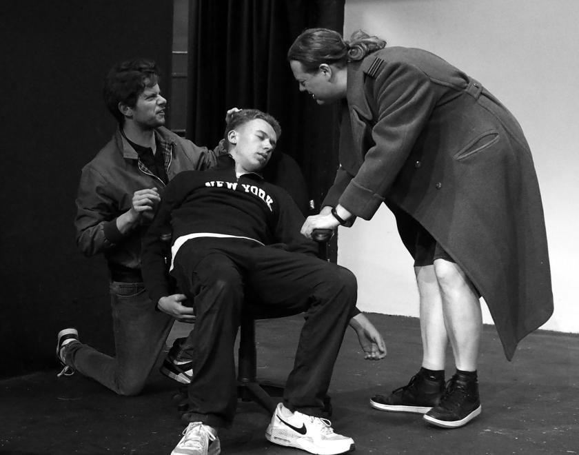 2 men try to revive another man unconscious in a chair