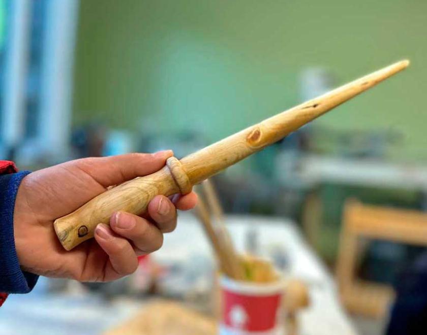 A hand holding a natural wood wand.