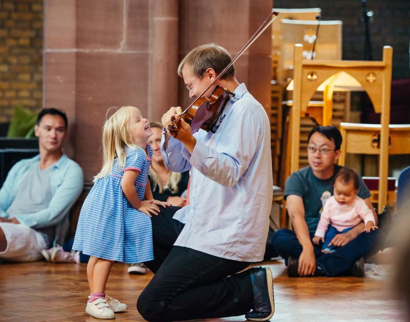 Child looking at a violinist at a Bach to Baby concert