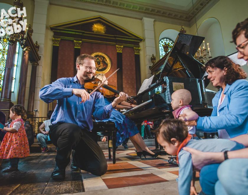 Child looking at a violinist at a Bach to Baby concert