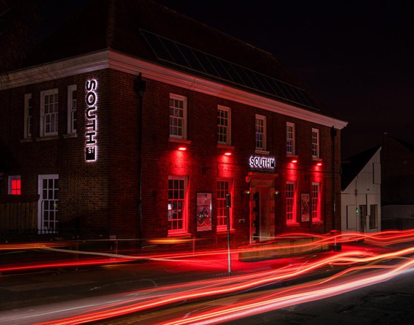 Timelapse photo of the South Street building at night, bathed in red light from its external lighting.