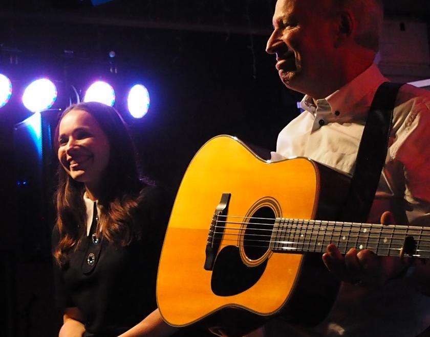 Image of Louise and Chris Rogan. Louise is singing and Chris is playing guitar.