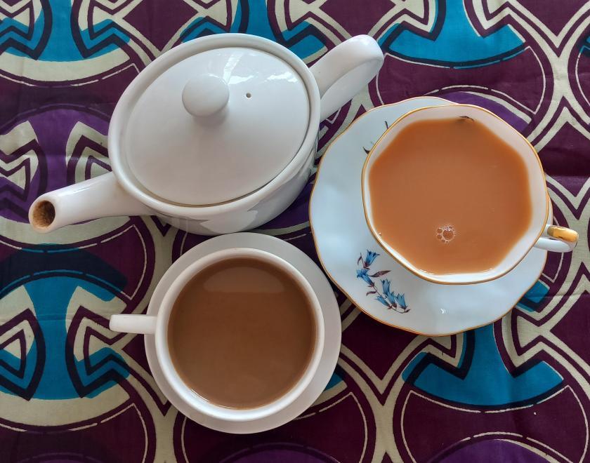 An Image of a coffee cup and teapot on a brightly coloured, African inspired tablecloth