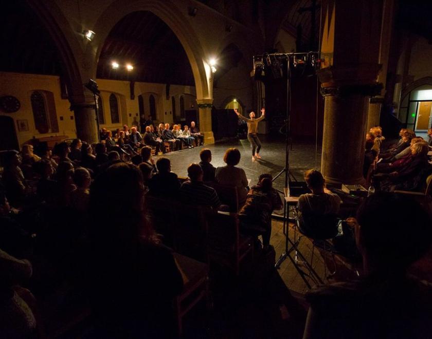 A full-house audience watching a dancer