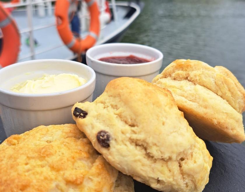 Scones with Clotted Cream, and Jam on a serving slate with river and part of boat view