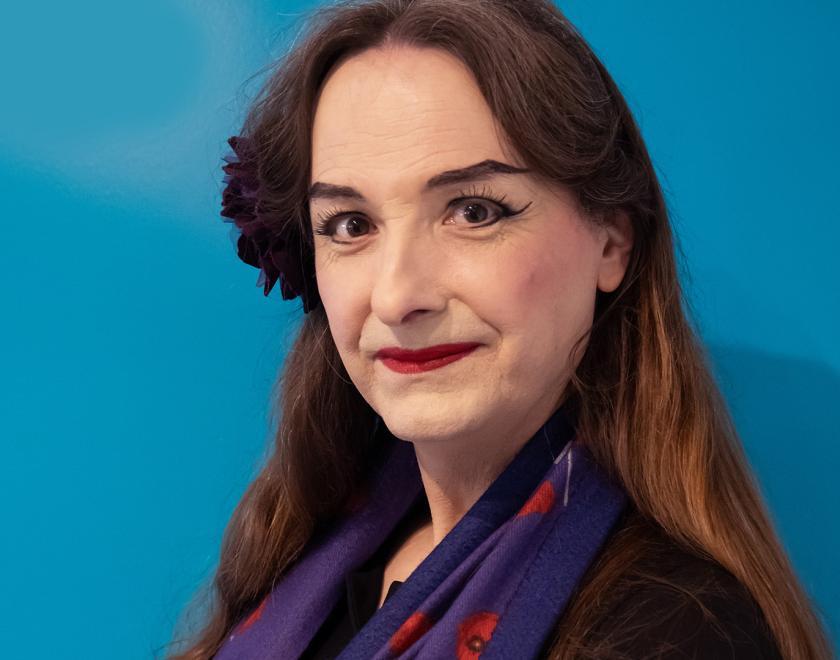 Photo of Alice d'Lumiere, a transwoman with pale make up and a flower in her hair