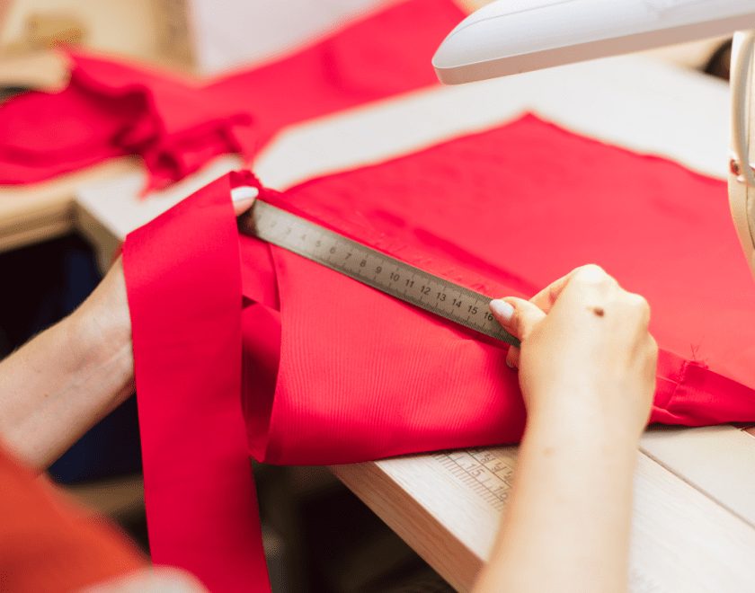 Hands measuring red fabric
