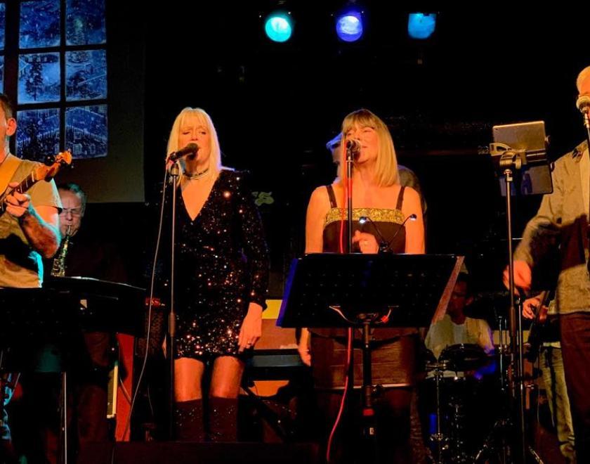 band performing on stage - two female vocalists and two male guitarists