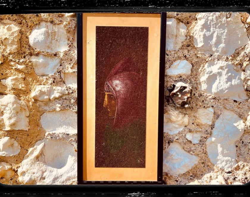 Photo of a framed portrait of a monk on a sandy coloured stone wall. A celluloid film frame is overlaid onto the image to make it look cinematic.