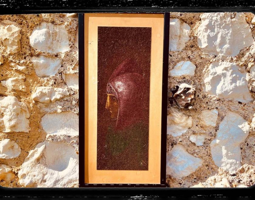 Photo of a framed portrait of a monk on a sandy coloured stone wall. A celluloid film frame is overlaid onto the image to make it look cinematic.