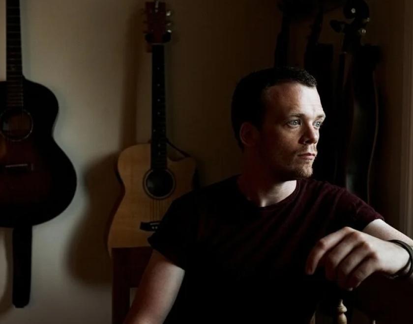 Chris Fox sitting in front of his guitars