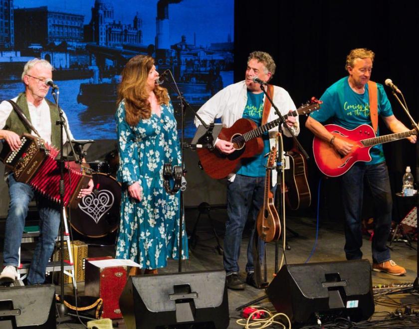 Photo of a band on stage with melodeon, guitars, banjo and double bass