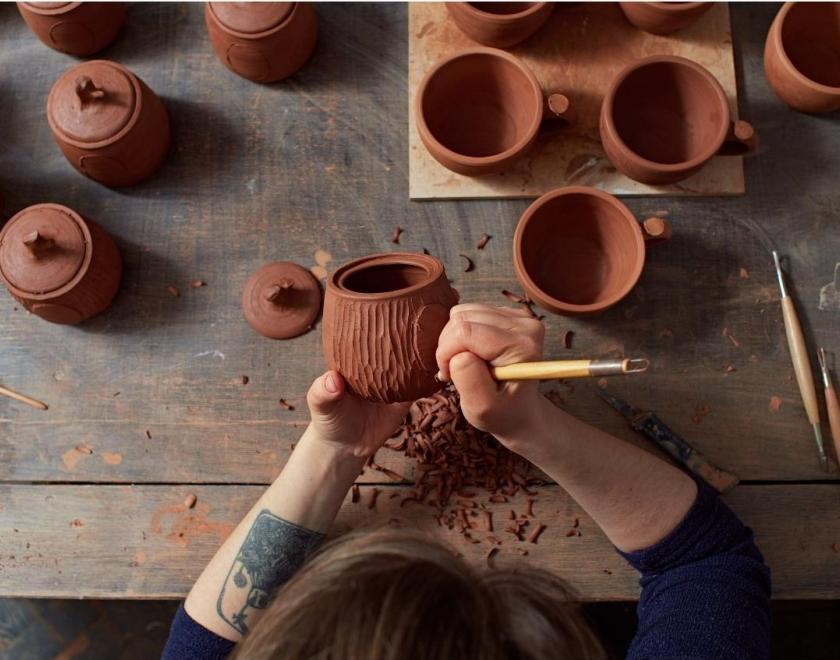 Person sculpting on clay pots
