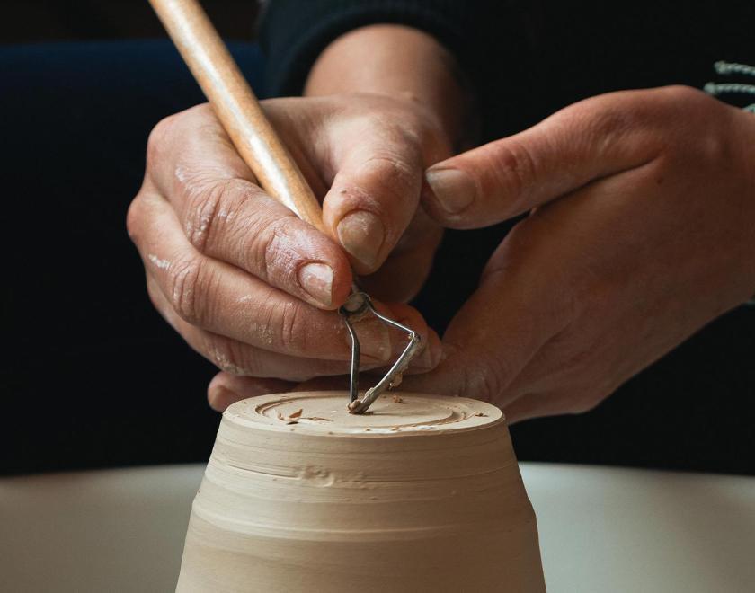 Hands sculpting a clay pot