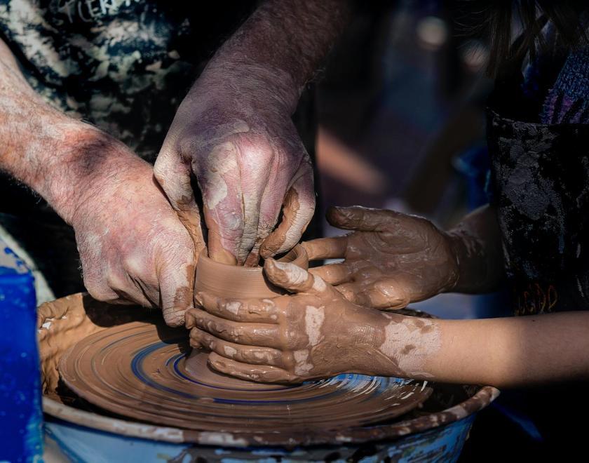 Hands working together on a pottery wheel