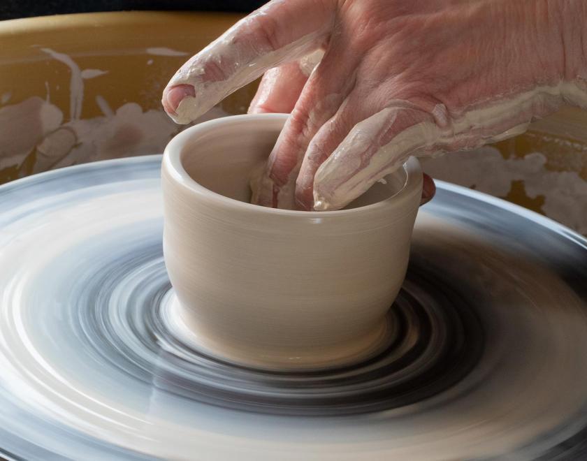 Hand throwing a clay pot at the wheel