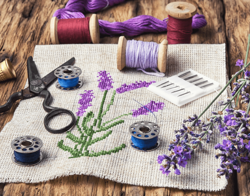 Colourful stitched embroidery with scissors and cotton on table
