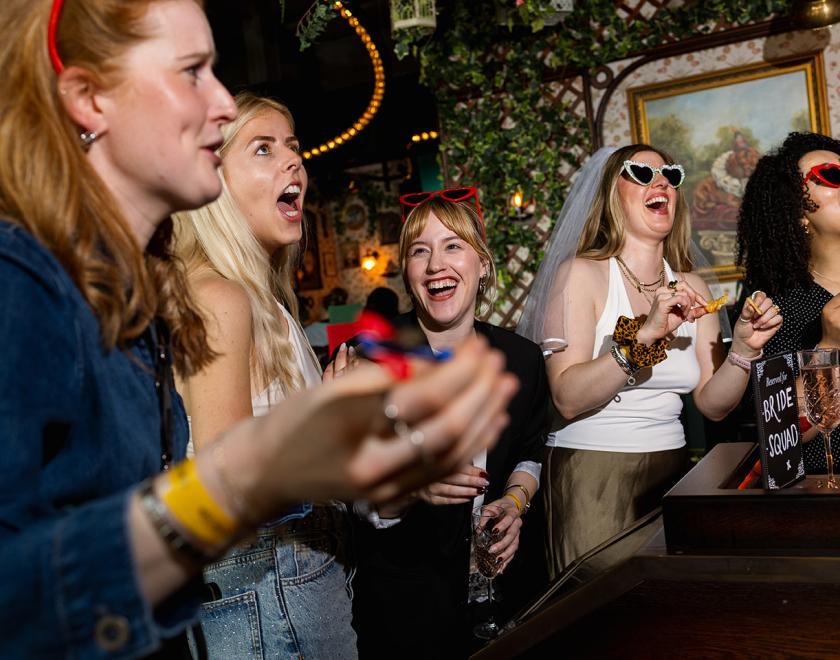 Women on a hen do paying darts