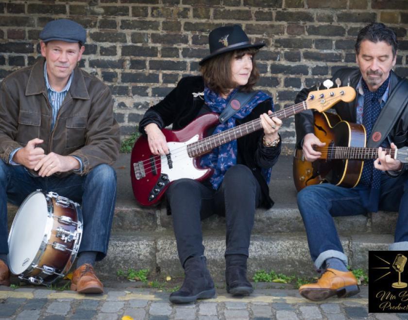 The Fran McGillivray Band sitting with instruments against a brick wall