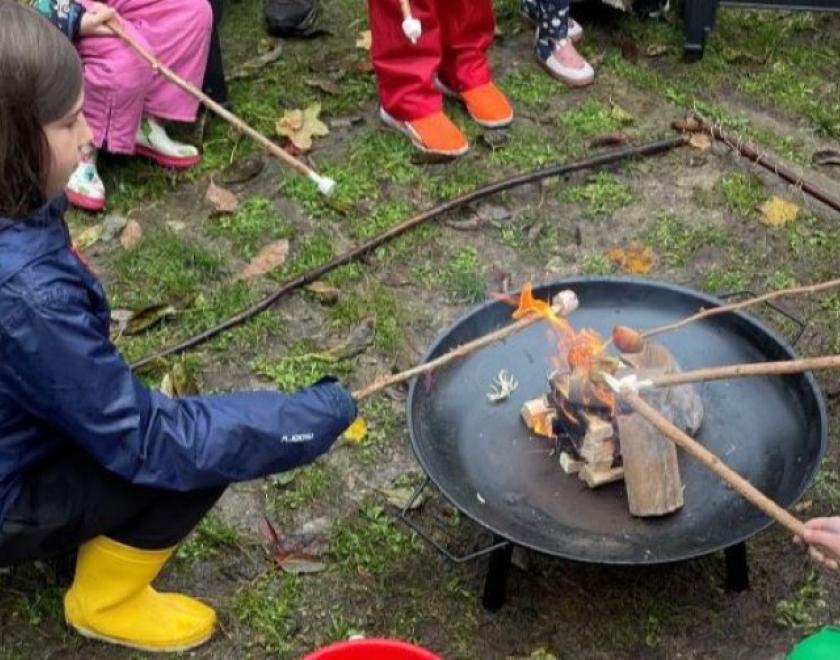 Families in the MERL garden toasting marshmallows on the campfire