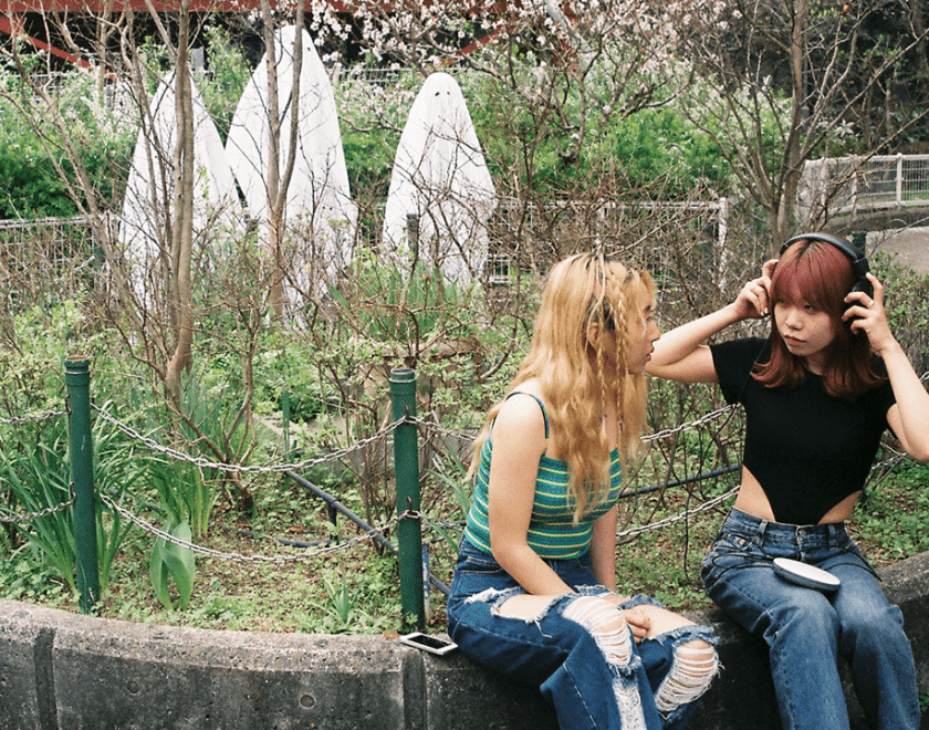 Two Japanese women sitting on a grass verge