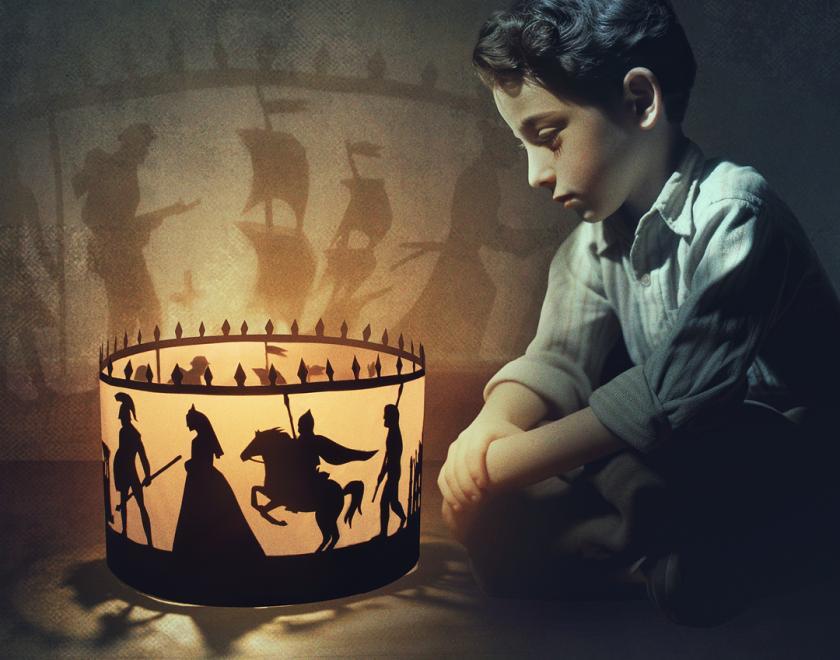 A child sits in front of a lit up zoetrope, the figures lit up are of historical memorabilia such as a princess, roman soldier and a knight on a horse. 