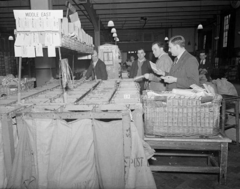 men in a middle east mail room in wartime