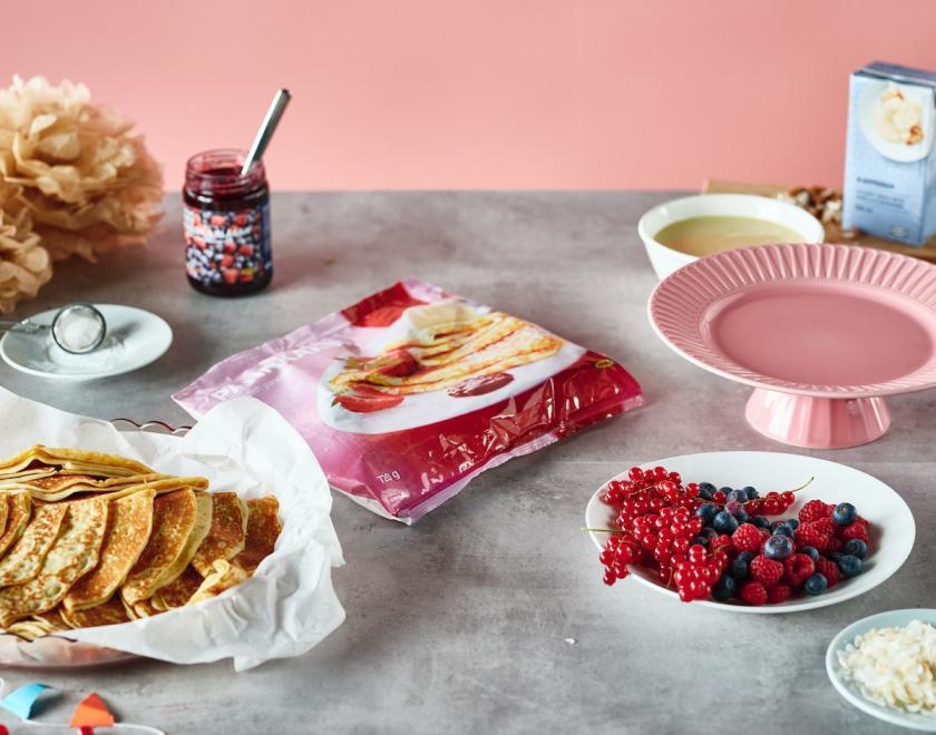 A spread of crepes , berries and jam on a table