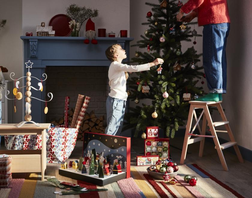 A young boy putting up festive decorations in their home 