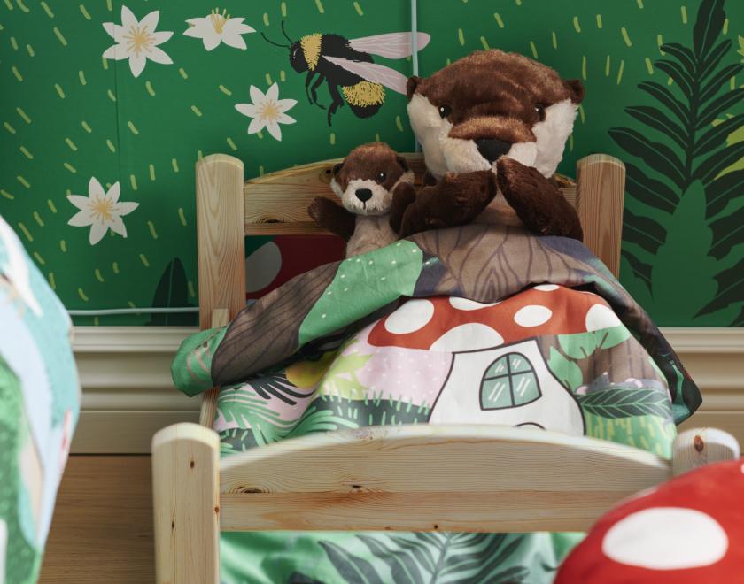 Baby and parent otter soft toys tucked in bed