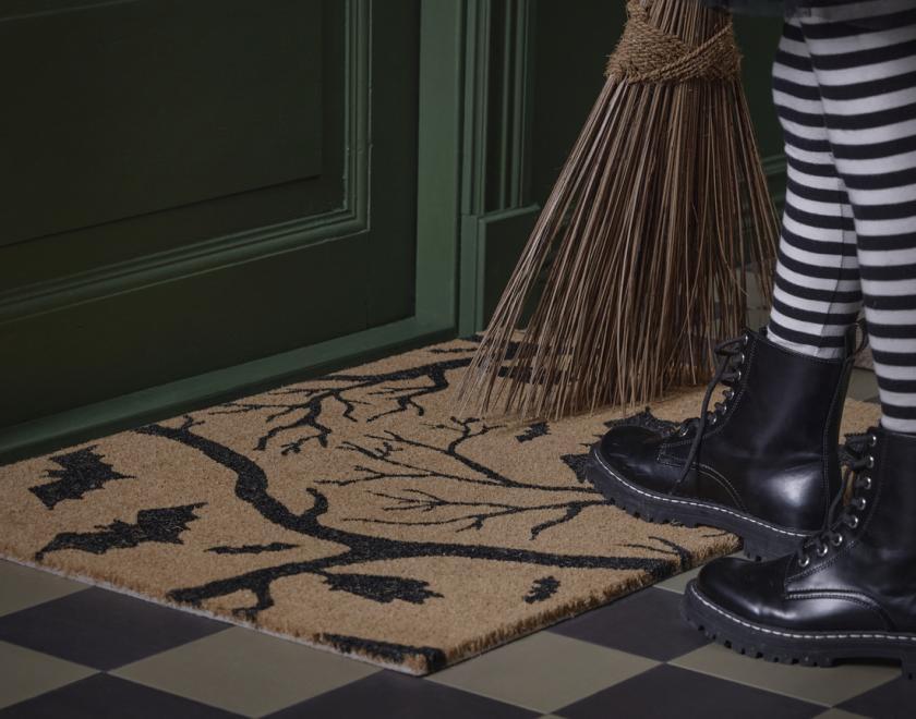 Halloween decorated door mat with trick or treater waiting at the door