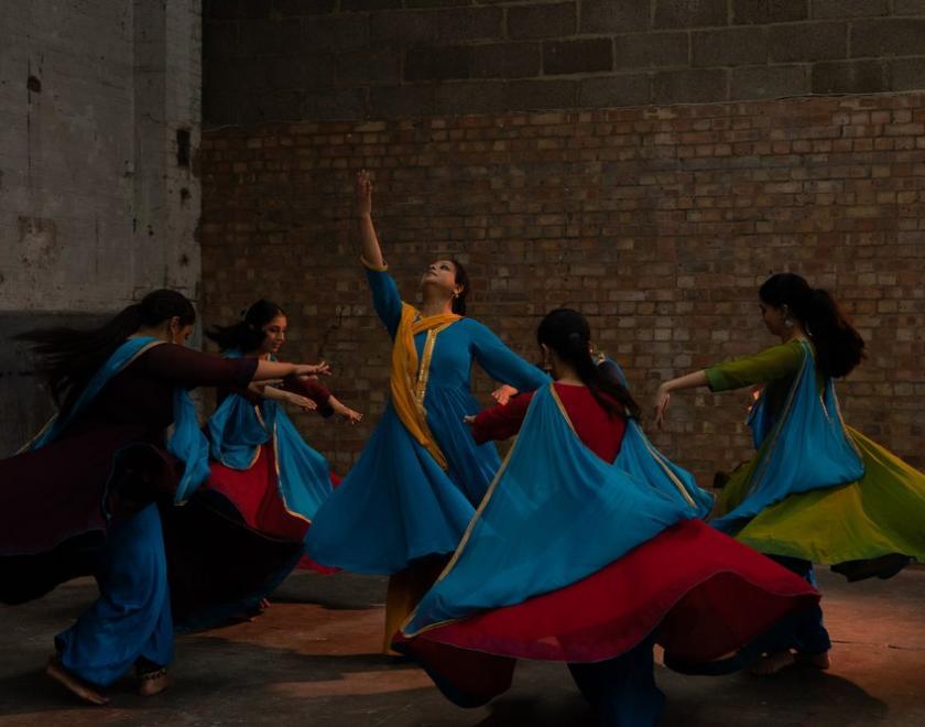 Five dancers in front of a brick wall