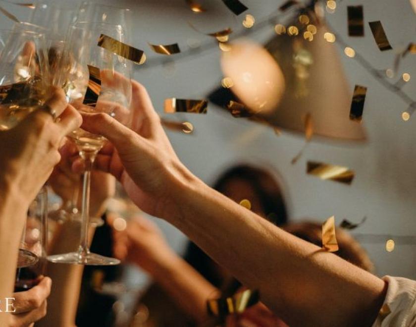 The image shows a group of people toasting their drinks 