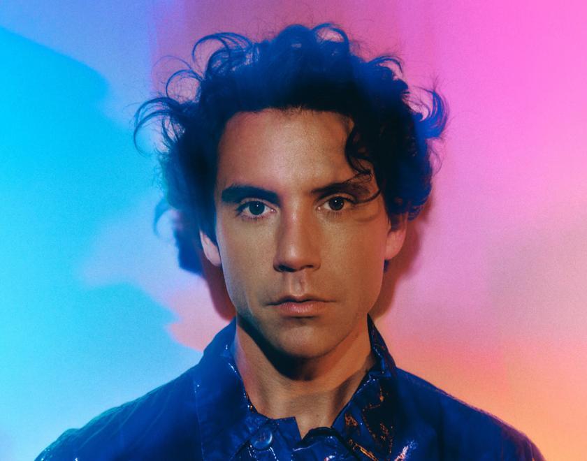 Singer Mika against a pink and blue background
