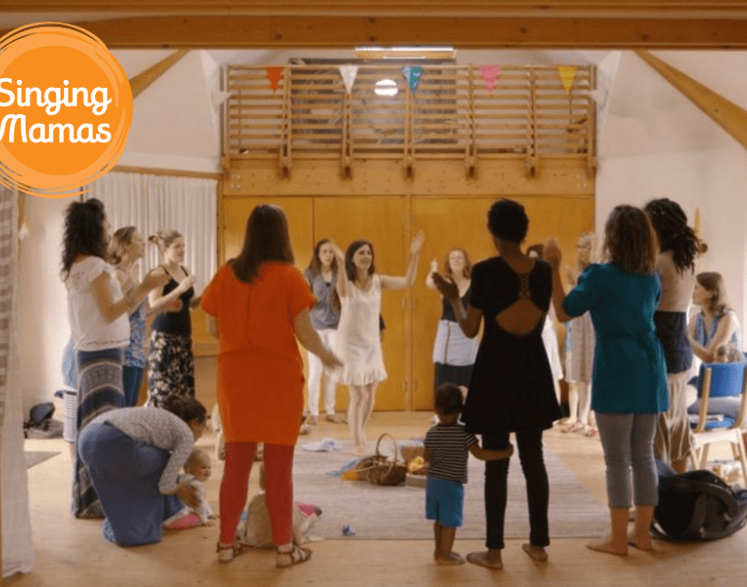 Singing Mamas logo and photo of a group of women standing in a circle and singing together