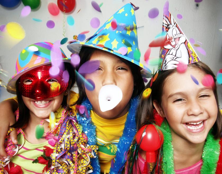 Three young girls in party hats with streamers celebrating
