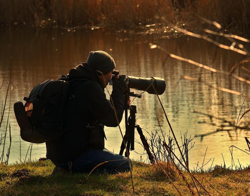 Wildlife photographer crouching by the riverside