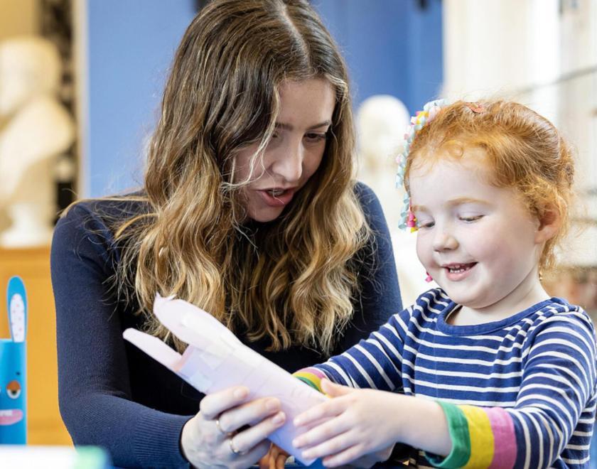 A child making crafts at Reading Museum, supported by a member of staff