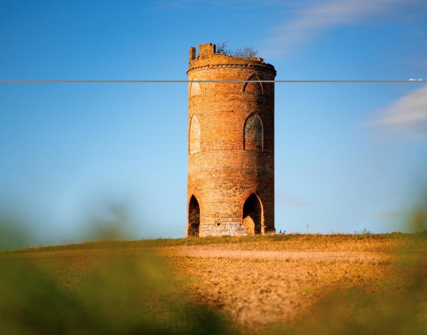 image of a tower in a field highlighted against a blue sky