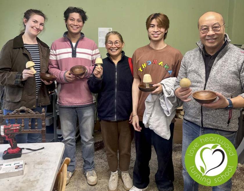 A family of five holding their turned mushrooms and bowls.